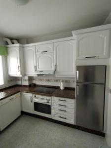 een keuken met witte kasten en een roestvrijstalen koelkast bij Piso Sol in Laxe