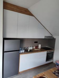 uma cozinha com armários brancos e um frigorífico de aço inoxidável em Bella apartman em Brcko