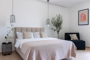 a white bedroom with a large bed and a chair at Soho Suites in Bar
