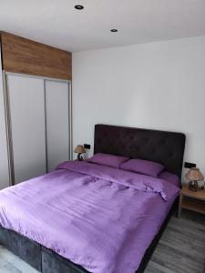 ein Bett mit violetter Bettwäsche in einem Schlafzimmer in der Unterkunft Bella apartman in Brčko