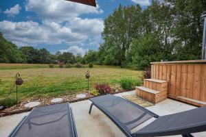 a patio with a table and chairs and a field at Le chouette insolite in Cresseveuille