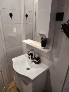 uma casa de banho branca com um lavatório e um espelho em Bella apartman em Brcko