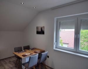 ein Esszimmer mit einem Tisch, Stühlen und einem Fenster in der Unterkunft Bella apartman in Brčko