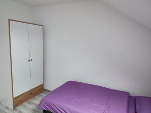 a bedroom with a purple bed and a mirror at Bella apartman in Brčko