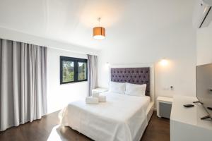 a bedroom with a white bed and a television at Villa Belo Horizonte in Porches +67 photos