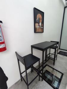 duas mesas e cadeiras pretas ao lado de uma parede em La Casa Mia Leon em León