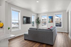 a living room with a gray couch and windows at Stay With Style In This Townhome in Billings