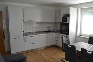uma cozinha com armários brancos e uma mesa com cadeiras em Apartma ob potoku em Luče