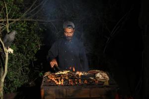 Um homem está a cozinhar comida numa grelha. em The Campers Lodge Yala em Yala