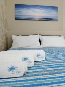 a bed with blue and white sheets and pillows at BlueSun Apartments in Leporano Marina