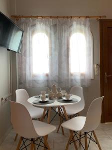 tavolo da pranzo bianco con sedie bianche e TV di Katerinas Inn Apartments a Keríon
