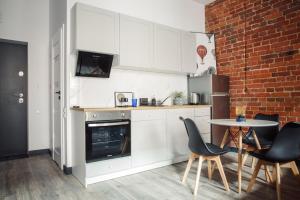 a kitchen with white cabinets and a table and a brick wall at East Street Apartamenty in Łódź