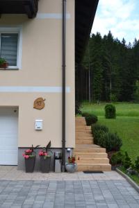 Luče的住宿－Apartma ob potoku，一座带木楼梯和花盆的房子