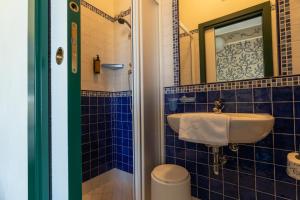 bagno piastrellato blu con lavandino e specchio di Hotel River fronte mare con piscina a Rimini