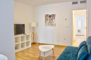 sala de estar con sofá azul y TV en Exclusivo Apartamento en el Centro de Sevilla, en Sevilla