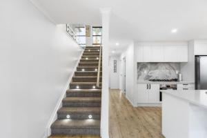 a staircase in a house with white walls and wood floors at Modern 5BR in Mangere - 6 mins from the Airport in Auckland