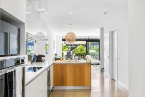 una cocina con paredes blancas y una isla de madera en el centro en 3 Bed Hobsonville Point Enchanter - WiFi - Netflix, en Auckland