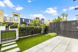 a backyard with a fence and grass at 3 Bed Hobsonville Point Enchanter - WiFi - Netflix in Auckland