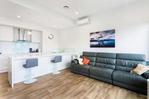 a living room with a couch and a kitchen at The Perfect Pad on the Shore seconds to Stadium in Auckland