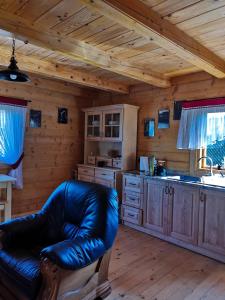 a living room with a leather couch in a kitchen at Siedlisko Sielska Dolina Nad Stawem luksusowy domek całoroczny z klimatyzacją 