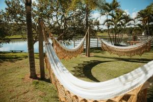two hammocks in a park next to a lake at Engenho da Serra Hotel EcoResort in Capitólio