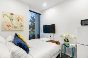 a white bedroom with a bed and a tv at Gorgeous Studio - Heart of Avondale - Netflix WiFi in Auckland