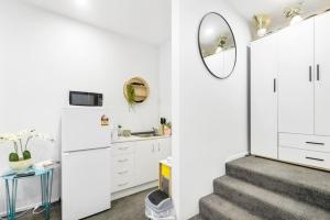 eine Treppe, die zu einer weißen Küche mit einem Spiegel führt in der Unterkunft Gorgeous Studio - Heart of Avondale - Netflix WiFi in Auckland
