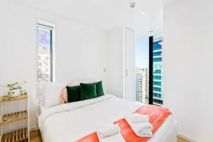 um quarto branco com uma grande cama branca e uma janela em City Seaview Stunner with Pool and Gym em Auckland
