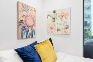 a white couch with two pillows and two paintings at Gorgeous Studio - Heart of Avondale - Netflix WiFi in Auckland
