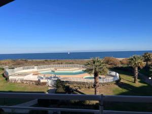 una vista di una piscina con palme e l'oceano di Face à la belle bleue - Appart avec parking a Saint-Cyprien Altre 13 foto