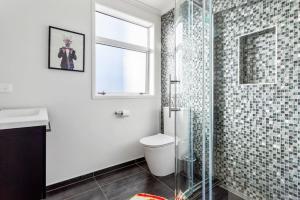 a bathroom with a toilet and a glass shower at 3 Bedroom Stunner in Hobsonville - WiFi - Netflix in Auckland +23 photos