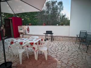 una mesa, sillas y una sombrilla en el patio en Villa Nel Verde - Bonsignore, en Tricase
