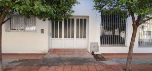 a white house with a white door and a tree at Manantial Departamentos in Gualeguay