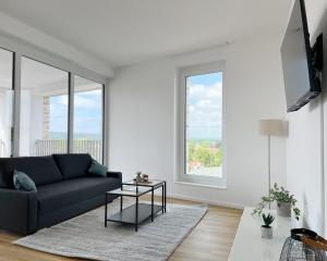a living room with a couch and a large window at Moderne Apartments im Herzen der Stadt I private Tiefgarage mit Ladesäulen I home2share in Ibbenbüren