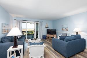 a living room with two blue couches and a television at 1305 Pelican Watch Villa in Seabrook Island