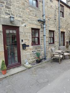 a brick building with two benches and a table at Cosy cottage in the heart of Pateley Bridge. in Pateley Bridge