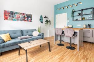 a living room with a blue couch and a kitchen at Cozy 2-Raumwohnung in Zentrumsnähe in Leipzig
