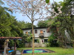 uma casa com uma árvore e uma piscina em Rio Natureza apart 113 no Rio de Janeiro