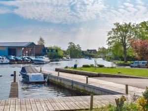 a boat is docked at a dock on a river at Lilys Cottage in Wroxham