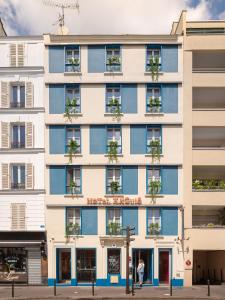 een appartementencomplex met blauwe ramen aan een stadsstraat bij Hôtel Exquis in Parijs
