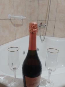 a bottle of wine with two glasses in a bath tub at DORMI-con HIDROMASAJE- POSADA RUTA 22 totalmente EQUIPADO in Plottier
