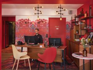 a man sitting at a desk with a computer at Hôtel Exquis in Paris