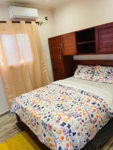 a bedroom with a bed with a floral comforter and a window at AS Guest House in Libreville