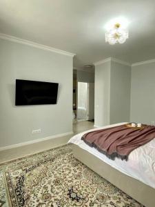 - une chambre avec un lit et une télévision à écran plat dans l'établissement Mangilik Cozy Apartment, à Astana
