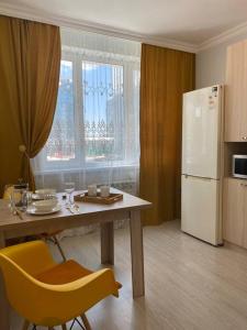 Il comprend une cuisine équipée d'une table et d'un réfrigérateur blanc. dans l'établissement Mangilik Cozy Apartment, à Astana