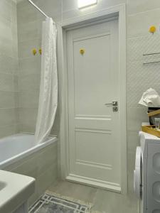 La salle de bains est pourvue d'une douche et d'une porte blanche. dans l'établissement Mangilik Cozy Apartment, à Astana