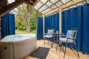 a hot tub on a deck with chairs and a table at Blue Moon Log Cabin in Nashville