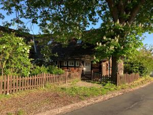 a wooden fence in front of a house with a tree at Ferienapartment Kastanje in Groß Ippener