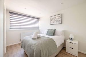 a white bedroom with a bed and a window at Charming 3Bed 3Bath Home in Windsor with parking! in Windsor