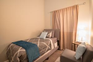 a small bedroom with a bed and a chair at Girlfriend Getaway Suite in Nashville